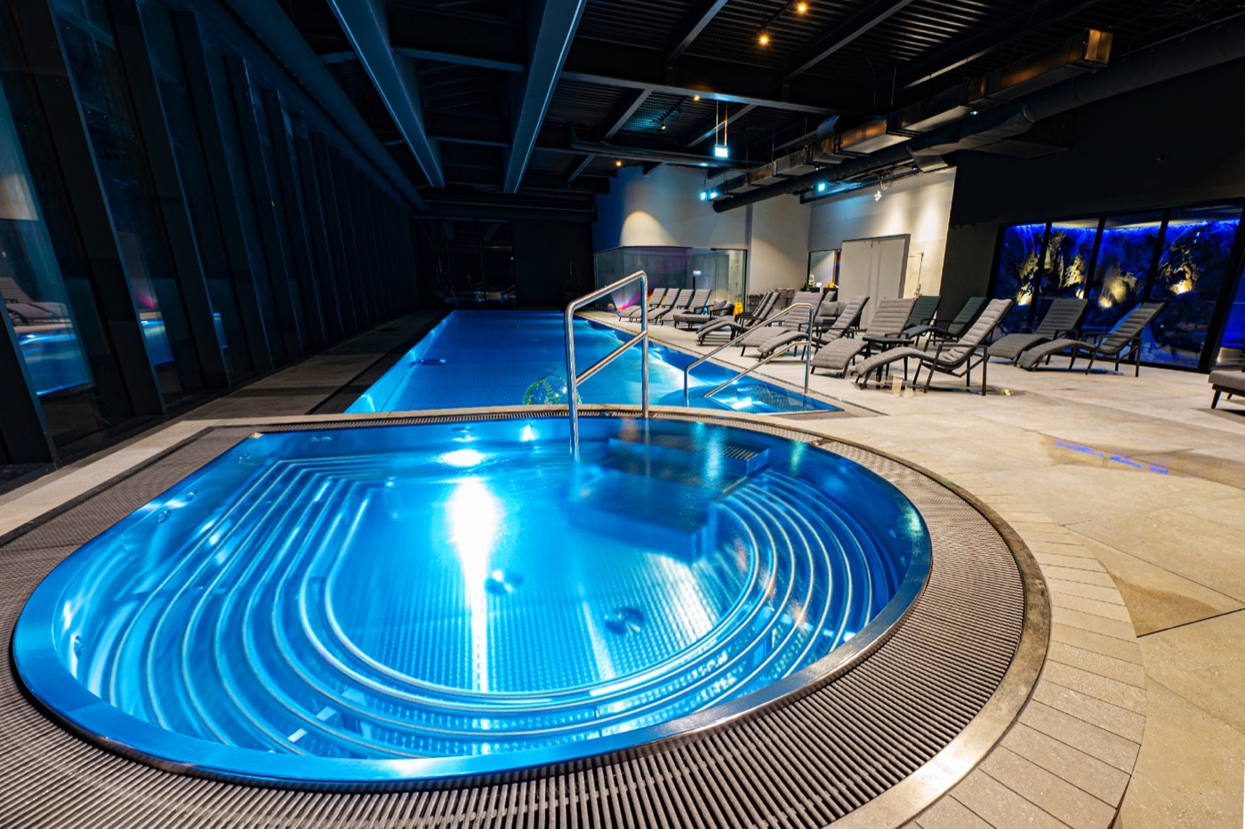 Stainless steel jet spa with curved welded bench and glowing hydrojets at dusk